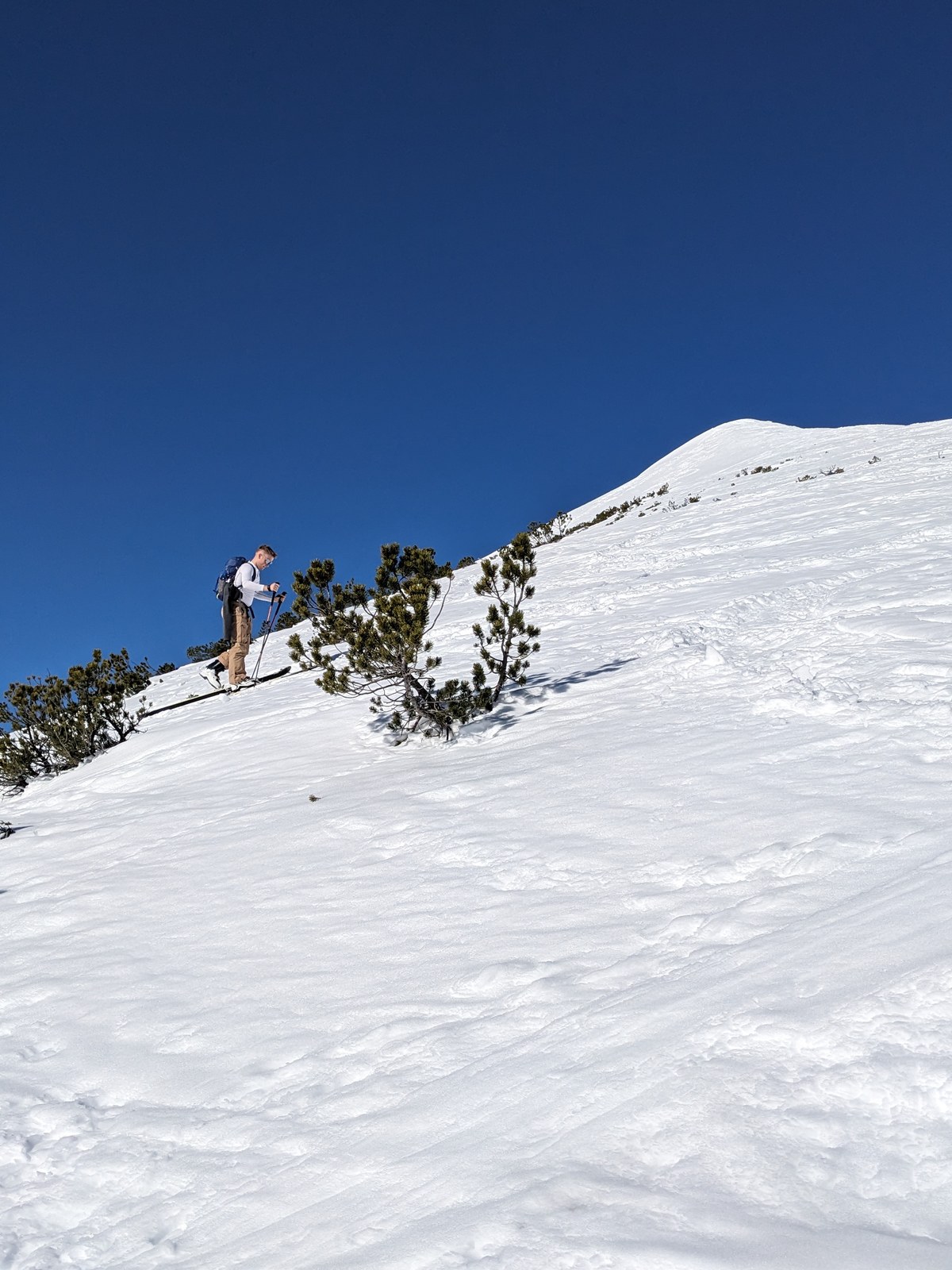 David on a ski tour on a snowy ridge under a deep blue sky